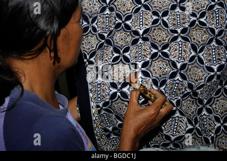 Appliquer de la cire femme avec un outil de montage incliné sur un modèle dans une usine de batik, près de Yogyakarta, le centre de Java, en Indonésie, en Asie du sud-est Banque D'Images