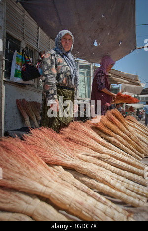 Femme vendant des balais dans le marché de la SST, au Kirghizistan. Banque D'Images