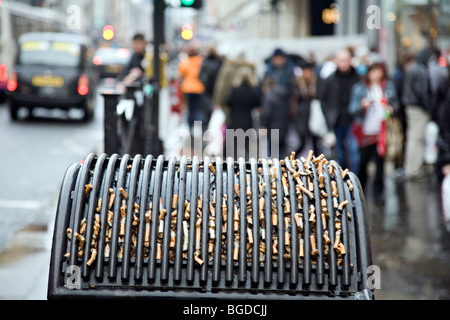 Une poubelle à Glasgow en Écosse plein de mégots de cigarettes Banque D'Images