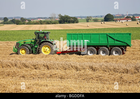 Tracteur avec remorque en attente d'un chargement de blé d'une moissonneuse-batteuse durant la récolte. Sud de la Suède, Scandinavie. Banque D'Images