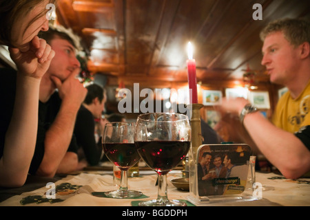 Scène de vie quotidienne hygge jeunes assis boire du vin autour d'une table dans un bar. Mode de vie moderne. L'Autriche, de l'Europe. Banque D'Images