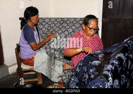 Les femmes l'application de cire avec un outil de montage incliné sur un modèle dans une usine de batik, près de Yogyakarta, le centre de Java, en Indonésie, en Asie du sud-est Banque D'Images