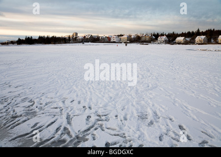 Les gens marcher sur un lac gelé. Tjornin lake, du centre-ville de Reykjavik, Islande. Banque D'Images