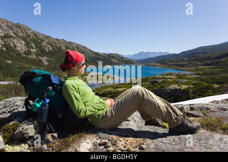 Jeune femme, randonneur, backpacker, enjoignant au repos panorama sur lac profond, historique du col Chilkoot, piste, Consul du Yukon Banque D'Images