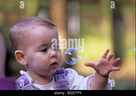 En salopette bébé fille pour atteindre bubble Banque D'Images