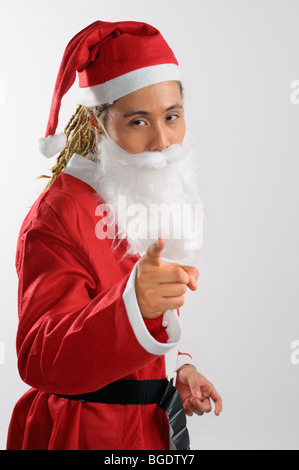 L'homme avec des dreadlocks habillé en costume père noël pointant son doigt pour Gentil ou méchant sur fond blanc Banque D'Images