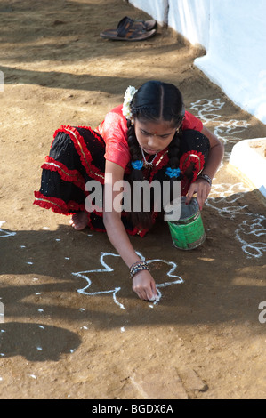 Village de l'Inde rurale girl making a rangoli design dans un village de l'Inde rurale pendant le festival de sankranthi. L'Andhra Pradesh, Inde. Banque D'Images