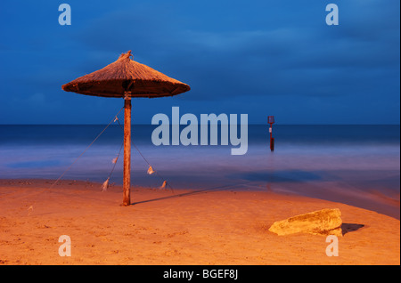 Une herbe hawaïenne parasol sur la plage de Swanage, Dorset - tourné au crépuscule. Banque D'Images