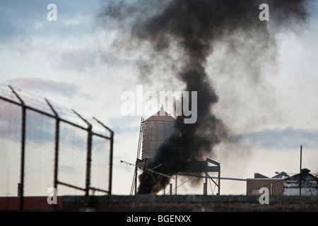 Fumée noire éructe dans le ciel depuis le toit d'un bâtiment sur le 143e rue à New York, USA, 28 décembre 2009. Banque D'Images