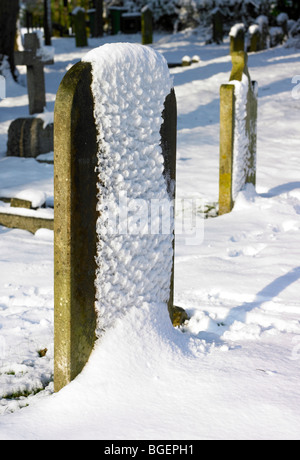 La neige a couvert une pierre tombale dans un cimetière Banque D'Images