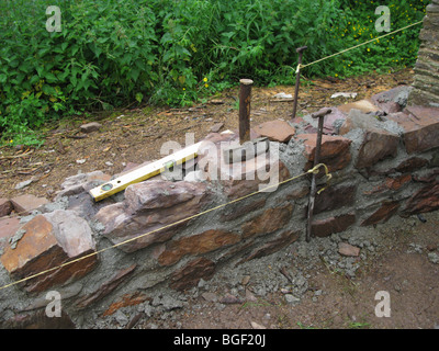 Aléatoire uncoursed rugueux mur de maçonnerie en construction dans jardin uk Banque D'Images