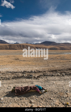 Un fervent pèlerin tibétain se prosterne le long du haut plateau du Tibet en route pour le temple Jokang à Lhassa. Banque D'Images