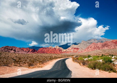 Road et de nuages d'orage avec des formations rocheuses dans le Red Rock Canyon National Conservation Area, Nevada Banque D'Images