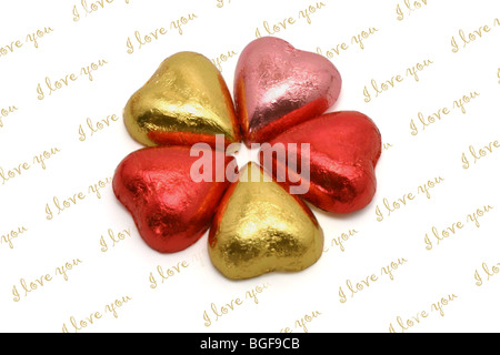 Chocolats en forme de coeur disposés en modèle floral sur I-love-vous contexte Banque D'Images