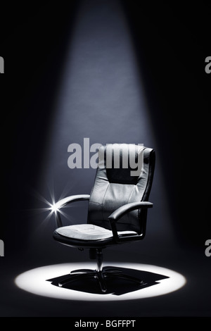 Fauteuil en cuir noir vide sous Spotlight Mastermind Banque D'Images