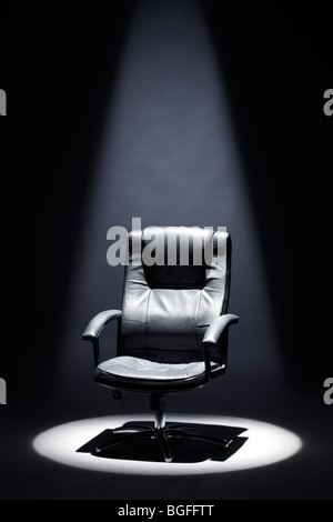 Fauteuil en cuir noir vide sous Spotlight Mastermind Banque D'Images