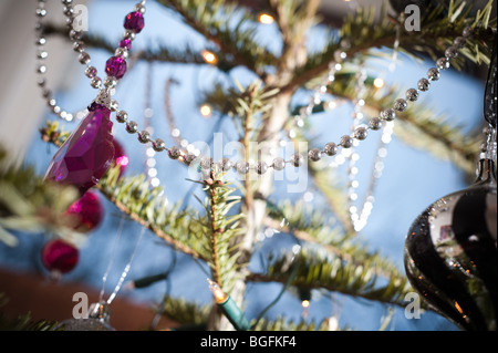 Décorations colorées joliment placé sur un pin (arbre de Noël dans un coin foom baie vitrée en décembre. Banque D'Images