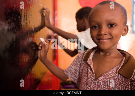 Un jeune garçon s'appuie sur un tableau noir dans un orphelinat dans la région de Kilimandjaro, Tanzani, Afrique de l'Est. Banque D'Images