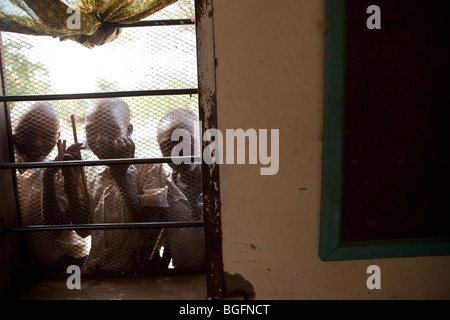 Les garçons de l'école par la fenêtre d'un dispensaire médical en Tanzanie : région de Manyara, district de Simanjiro, village visité. Banque D'Images