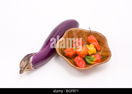 Piments Scotch Bonnet Caraïbes mixtes dans bol en bois avec shiny aubergine against white background Banque D'Images