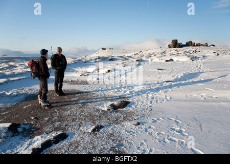 Les marcheurs, deux hommes en conversation neige de l'hiver par la Roue des pierres sur le bord au-dessus de Ladybower Derwent barrage dans le Derbyshire Peak District Banque D'Images