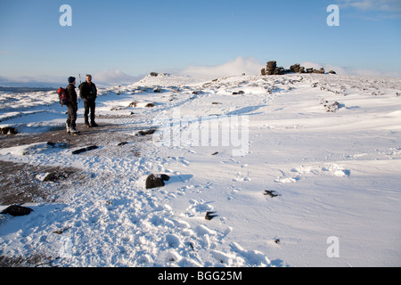 Les marcheurs, deux hommes en conversation neige de l'hiver par la Roue des pierres sur le bord au-dessus de Ladybower Derwent barrage dans le Derbyshire Peak District Banque D'Images