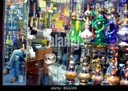 Un homme fumeur de narguilé narguilé dans une boutique avec des tuyaux d'eau, partie asiatique de Kadikoy Istanbul. Banque D'Images