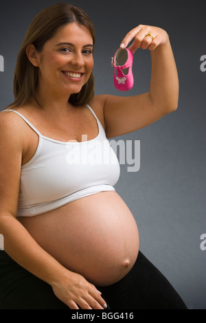 Portrait of a pregnant woman holding baby girl shoe, smiling, portrait Banque D'Images