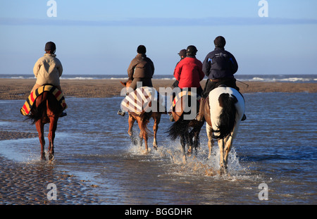 Cinq cavaliers sur la plage Équitation à Burnham Overy de Holkham le jour de l'an 2010. Banque D'Images