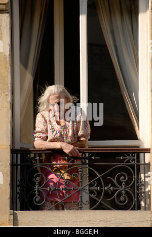 Personnes âgées femme française contempler de son balcon fenêtre pour la rue ci-dessous Banque D'Images