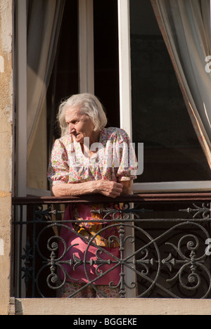 Personnes âgées femme française contempler de son balcon fenêtre pour la rue ci-dessous Banque D'Images