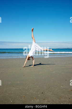 Femme faisant la roue sur la plage Banque D'Images