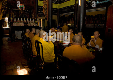 Moines assis à une table à manger, la Pagode Giac Lam, Ho Chi Minh City, Vietnam Banque D'Images