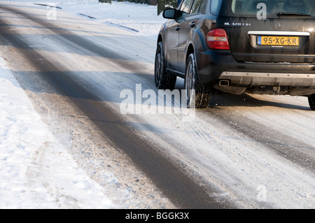 Une voiture lentement son chemin le long d'une route couverte de neige aux Pays-Bas Banque D'Images