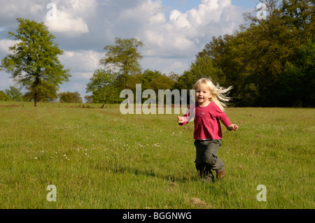 Stock photo d'un enfant de 3 ans aux cheveux blonds fille courir dans un champ. Banque D'Images