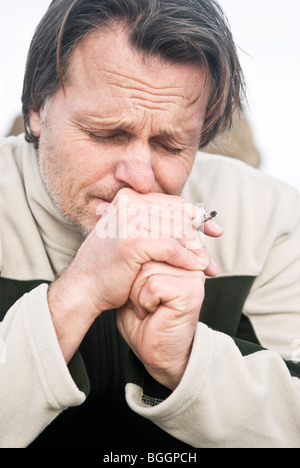 Une photo portrait couleur d'un déprimé man smoking a cigarette Banque D'Images