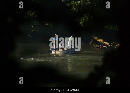 Trois hommes LA PÊCHE À LA MOUCHE À PARTIR D'UN BATEAU DÉRIVE VU PAR L'OUVERTURE À LA GÉORGIE D'ARBRE modèle ne libération Banque D'Images