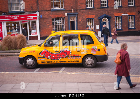 Un taxi jaune à travers la ville avec des lecteurs en mouvement,Norwich Norfolk,UK Banque D'Images