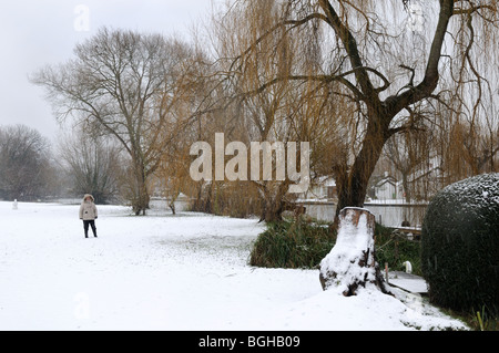 Figure walking in snow by river Banque D'Images