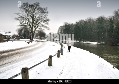 Figure walking in snow by river Banque D'Images