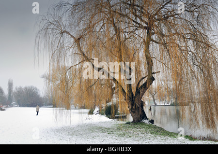 Figure walking in snow by river Banque D'Images