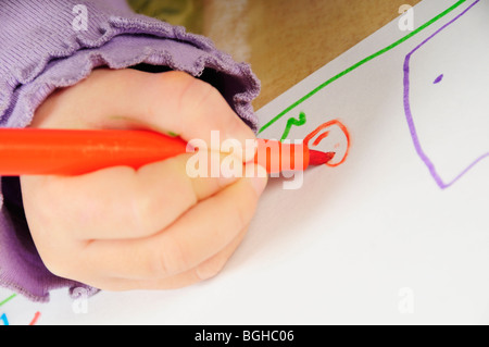 Stock photo d'un gros plan d'une petite filles main tenant un feutre qu'elle dessine une photo. Banque D'Images