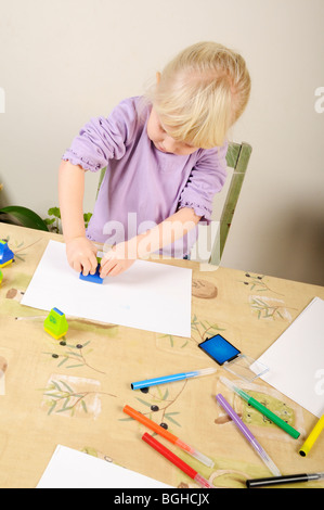 Stock photo d'une fillette de quatre ans à l'aide de timbres d'encre lors d'une session de jeu créatif. Banque D'Images