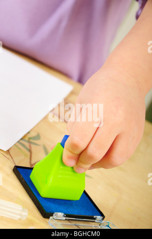 Stock photo d'une fillette de quatre ans à l'aide de timbres d'encre lors d'une session de jeu créatif. Banque D'Images