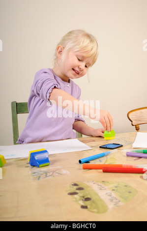 Stock photo d'une fillette de quatre ans à l'aide de timbres d'encre lors d'une session de jeu créatif. Banque D'Images