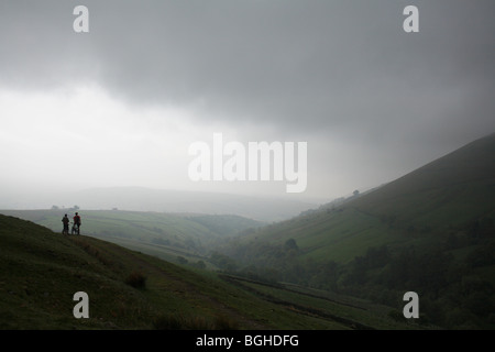 Deux cyclistes de montagne monter un sentier dans la montagne brumeuse Fells Cap Sud, Royaume-Uni Banque D'Images
