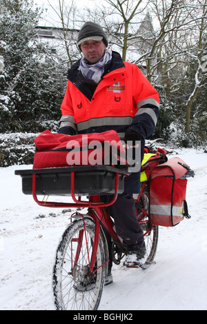 Un facteur de la poste la distribution du courrier en hiver. Woodborough, Nottinghamshire, Angleterre, Royaume-Uni Banque D'Images