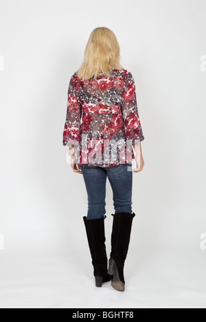 Vue arrière d'un blond woman wearing colorful haut, un jean et des bottes noires Banque D'Images