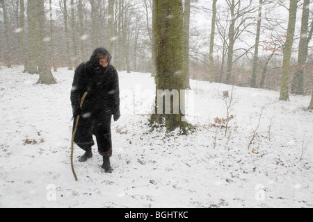 Une femme marche dans une tempête de neige à travers les bois. Banque D'Images