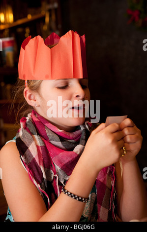 Enfant portant un chapeau de fête en papier la lecture d'une blague d'un cracker de Noël